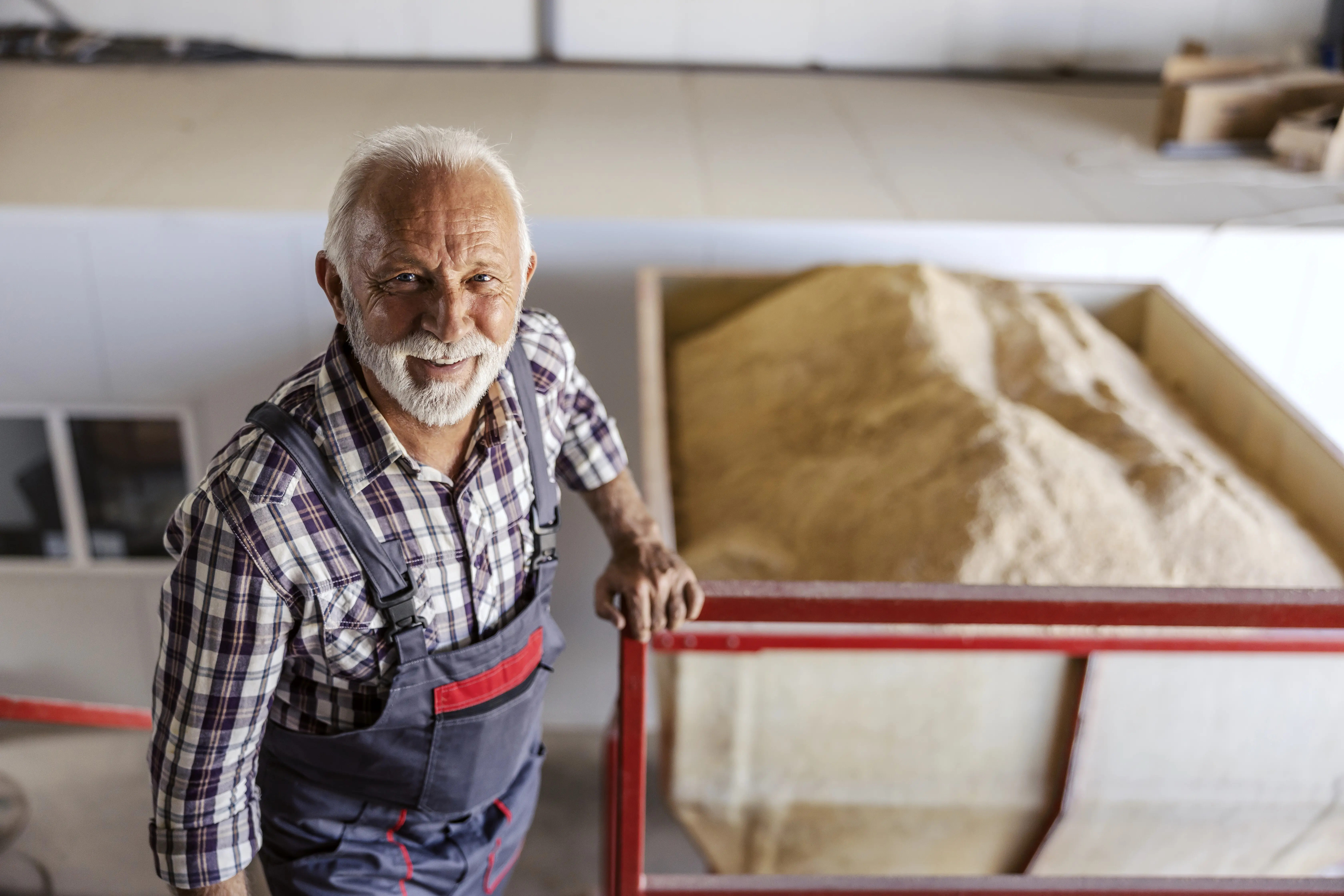 A happy senior sugar refinery worker is standing on the stairs, looking at the camera.