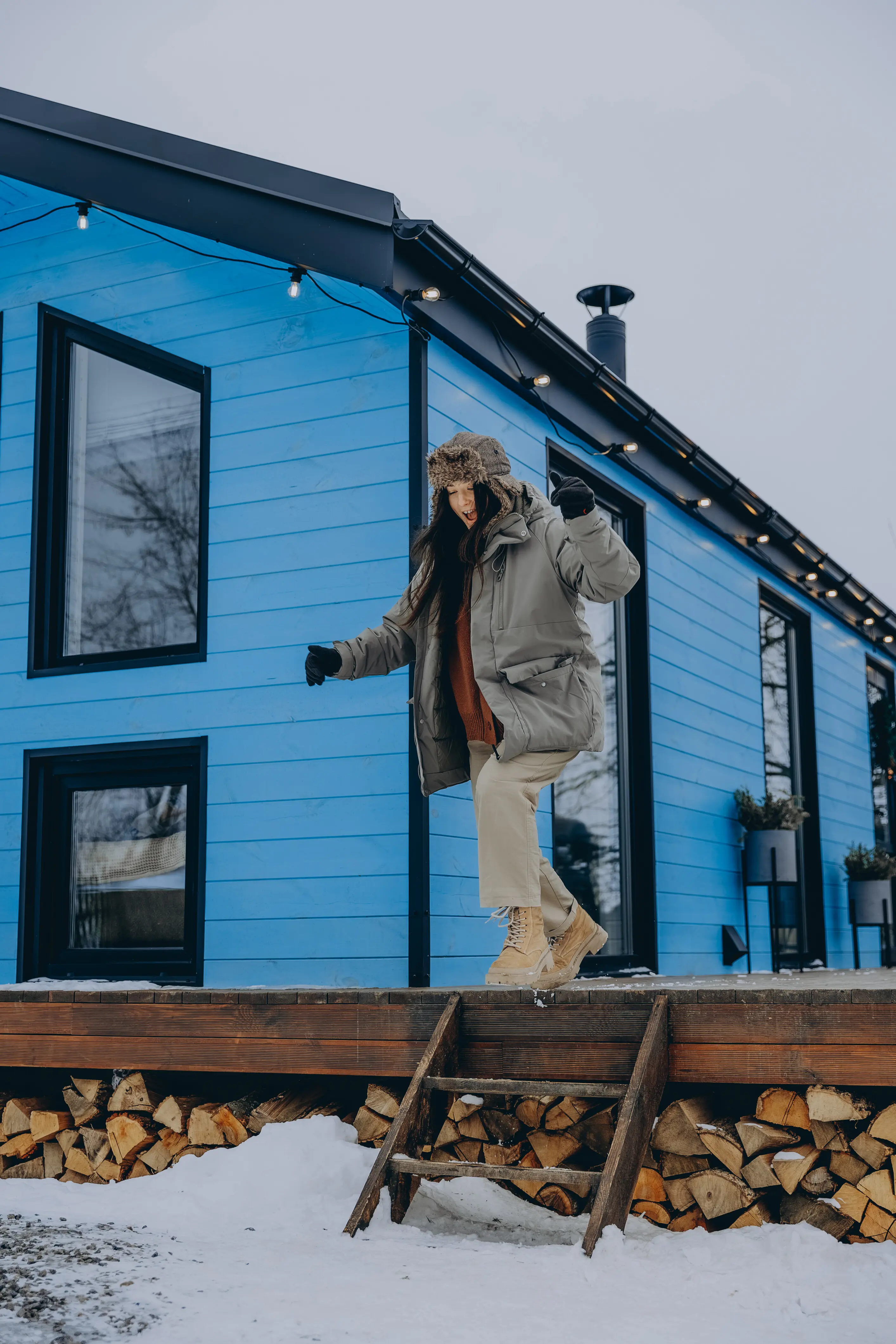 020124, Bar, Ukraine: a young woman in warm country attire with a vacation country house in the background, enjoying the winter view of the village.